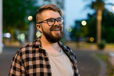 Portrait of man standing in night city street with bokeh street lights background. Confident lonely guy. Close-up portrait