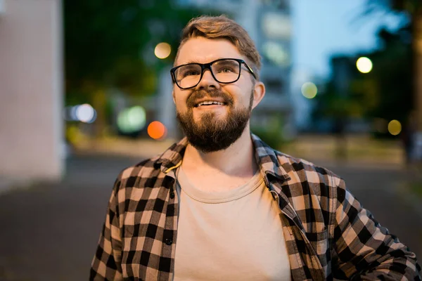 Portrait of man standing in night city street with bokeh street lights background. Confident lonely guy. Close-up portrait