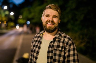 Portrait of man standing in night city street with bokeh street lights background. Confident lonely guy. Close-up portrait