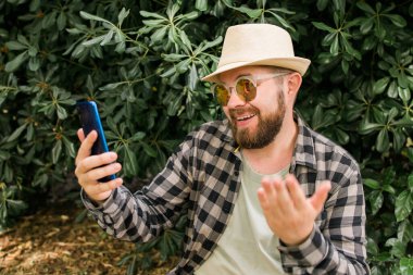 Sakallı adam akıllı telefondan video görüşmesi yapıyor. Video bağlantısı ve teknoloji kavramı..