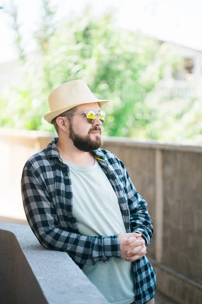 Bearded man in summer clothes and hat stand over beige wall on street city urban and travel concept - copy space and empty space for advertising.