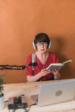Middle-aged female radio presenter talking into the microphone and reading news - radio broadcast online
