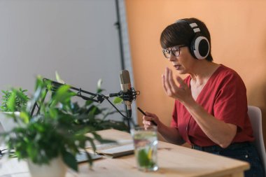 Middle-aged female radio presenter talking into the microphone and reading news - radio broadcast online