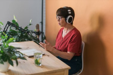 Middle-aged female radio presenter talking into the microphone and reading news - radio broadcast online