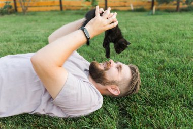 Man with little kitten lying and playing on grass - friendship love animals and pet owner concept. High quality photo