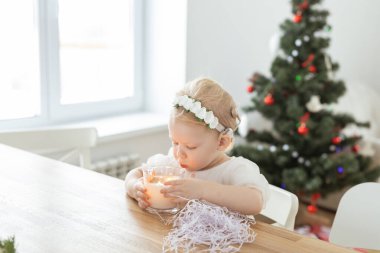 Child girl dressed in christmas dress with cochlear implants having fun at home - hearing aid and innovating technologies for treatment deafness