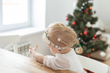 Child girl dressed in christmas dress with cochlear implants having fun at home - hearing aid and innovating technologies for treatment deafness