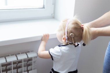 Anne kızının koklear implant işitme cihazını tamir ediyor. Sağırlık ve çeşitlilik kavramı. Tedavi sağırlığında yenilikçi teknolojiler