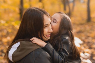 Anne ve kızı sonbahar sarı parkında birlikte vakit geçiriyorlar. Mevsim ve tek ebeveyn