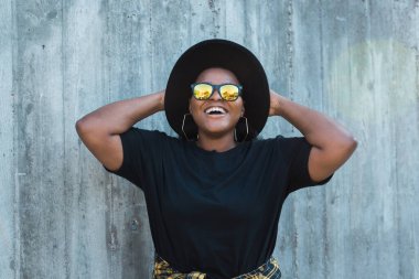 Şık, kıvırcık saçlı, yuvarlak güneş gözlüklü Afro-Amerikan bir kızın yakın plan portresi. Instagram tarzında yaz hipster fotoğrafları