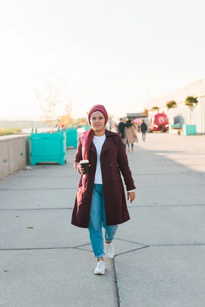 年轻的阿拉伯美女穿着头巾在街上走来走去 敲着智能手机 边喝咖啡边走 漂亮的穆斯林女性 头戴头巾 在空中漫步 发短信 — 图库照片