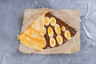 Çikolata kaplı krepler ve beyaz tabakta muz. İnce krep, blini. Tatlı tatlı.