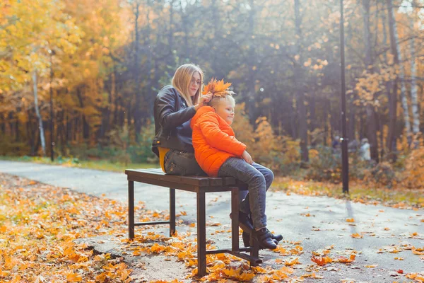 在秋天的公园里 单亲妈妈和小孩坐在长椅上 秋天和家庭观念 — 图库照片