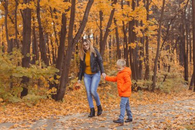 Anne ve oğlu sonbahar parkında yürüyor ve güzel sonbahar doğasının tadını çıkarıyorlar. Sezon, yalnız ebeveynler ve çocuklar konsepti