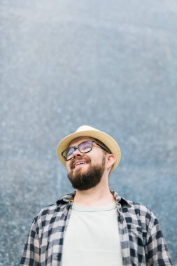 guy tourist looking happy wearing straw hat for travelling, standing against concrete wall background with copy space