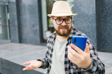 Sakallı adam akıllı telefondan video görüşmesi yapıyor. Video bağlantısı ve teknoloji kavramı..