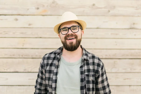 Laughing attractive man wearing hat over wooden background - emotion and vacation travel holidays