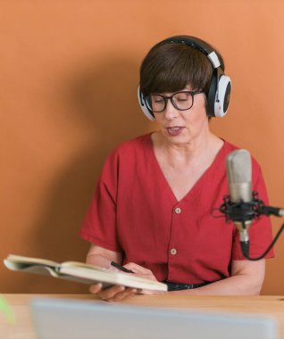 Middle-aged female radio presenter talking into the microphone and reading news - radio broadcast online