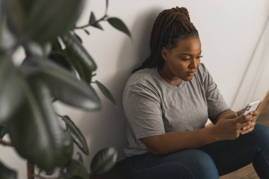 İyi görünümlü Afrikalı kız öğrencilerin portresi, günlük kıyafetleri içinde cep telefonu taşıması, mesajlar yazması ve yüksek internet bağlantıları kullanarak sosyal ağlarla iletişim kurması..