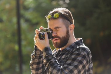 Afro-Amerikalı fotoğrafçı, yeşil parktaki klasik kamerayla fotoğraf çekiyor. Boş zaman aktivitesi, çeşitlilik ve hobi.