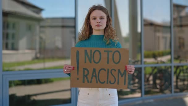 Fiatal szőke áll az utcán, nem a rasszizmus banner — Stock videók