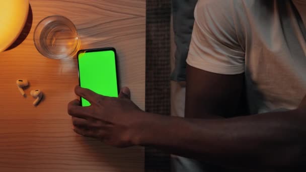 African american man going to bed and putting mobile with green scree — Stock Video