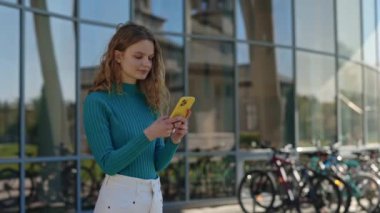 Şehir caddesinde akıllı telefondan mesaj atan olumlu bir kadın.