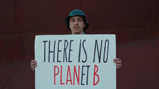Человек, держащий там нет планеты B баннер на открытом воздухе — стоковое видео