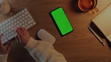 Klavyede yazan ve yeşil ekran mobil kullanan kadın