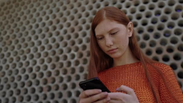 現代的なスマートフォンを屋外で使用して魅力的な若い女性 — ストック動画