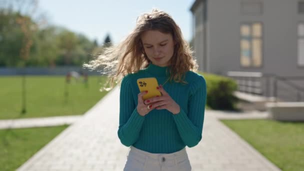 Charmig blond promenad på gatan med smartphone i händerna — Stockvideo