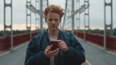 Kızıl saçlı, yüzünde mutlulukla seyyar ekrana bakıyor.