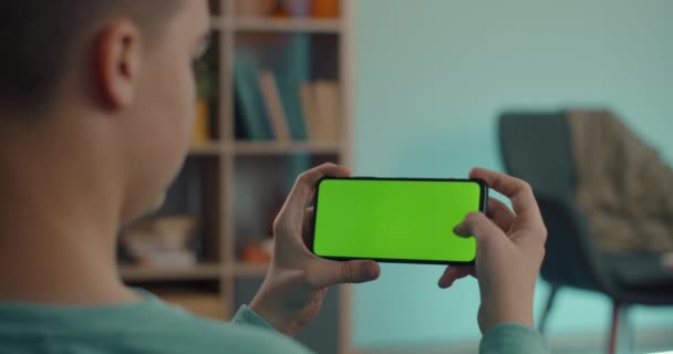 Man houdt mobiel in horizontale positie met groen scherm — Stockvideo