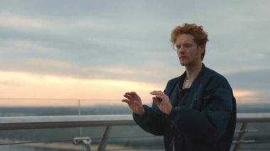 Kırmızı kıvırcık saçlı ciddi bir adam şehir caddesinde dikilirken görünmez dokunmatik ekran kullanıyor. Genç adam sanal ekranda, elle tıkırdıyor, tıkırdıyor. Teknoloji, arayüz kavramı