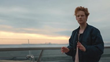 Kırmızı kıvırcık saçlı ciddi bir adam şehir caddesinde dikilirken görünmez dokunmatik ekran kullanıyor. Genç adam sanal ekranda, elle tıkırdıyor, tıkırdıyor. Teknoloji, arayüz kavramı.