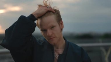 Açık havada kızıl saçlarını düzelten adamın portresi.