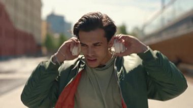 Açık havada müzik dinlemek için kulaklık kullanan mutlu bir adam.