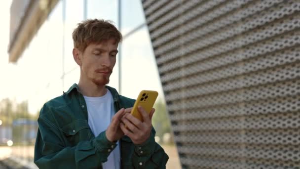 Blanke man loopt buiten met mobiel in handen — Stockvideo