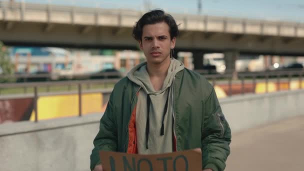Молодой парень, стоящий на городской улице без расистского баннера — стоковое видео