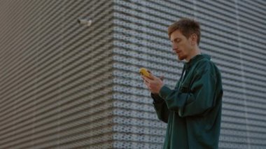 Yakışıklı sakallı adam caddede duruyor ve cep telefonu kullanıyor.