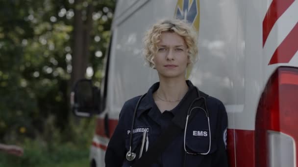 Utomhus porträtt av kvinnlig ambulans nära ambulans — Stockvideo