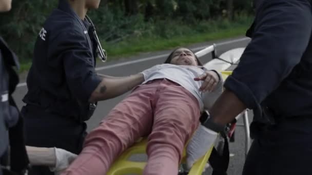 Ambulanciers paramédicaux multiculturels portant un enfant blessé sur civière — Video