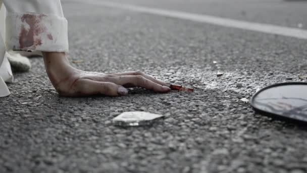 Закрытие женских рук в крови и разбитое стекло на дороге — стоковое видео
