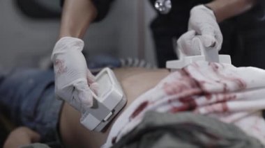 Sağlık görevlileri hastanın kalbini defibrilatörle uyarıyorlar.