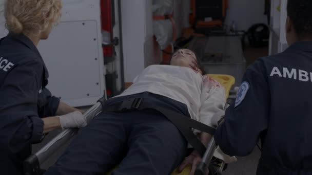 Equipe d'ambulanciers tirant civière avec femme blessée — Video