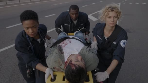 Tres paramédicos tirando de camilla con hombre herido — Vídeos de Stock