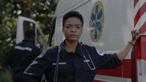 Paramedico afroamericano in piedi vicino ambulanza auto — Video Stock