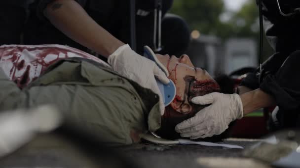 Paramedics in gloves fixing neck collar to asian man — Stock Video