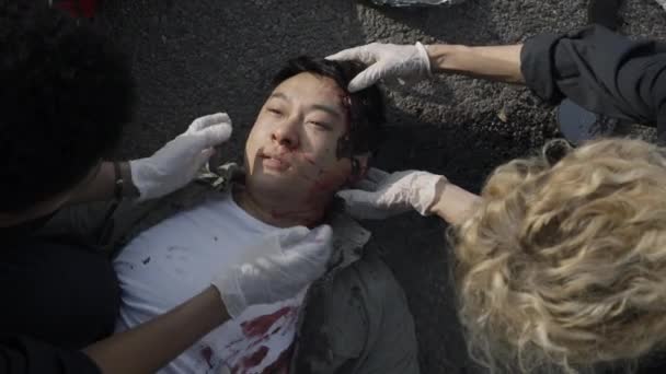 Grupo de ems paramédicos ayudar asiático hombre con lesionado cabeza — Vídeos de Stock