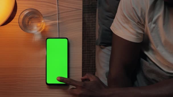 Чоловік лежить в ліжку і торкається зеленого мобільного екрану — стокове відео